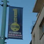 the banner for the Hidden Coity festvial Plymouth hangs from a lamp post with a bight blue sky behind it